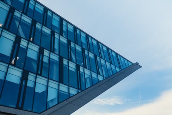 Glass curtain-wall facade of a modern office building viewed from below